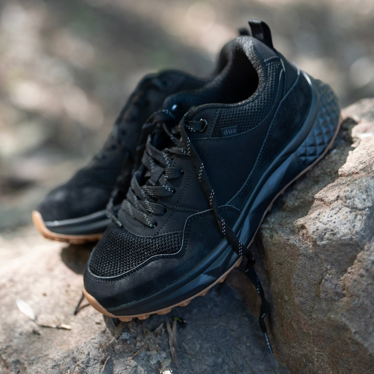 Zapatillas Due Shoes Dolomiti II negras de malla transpirable con suela flexible sobre una roca en un bosque