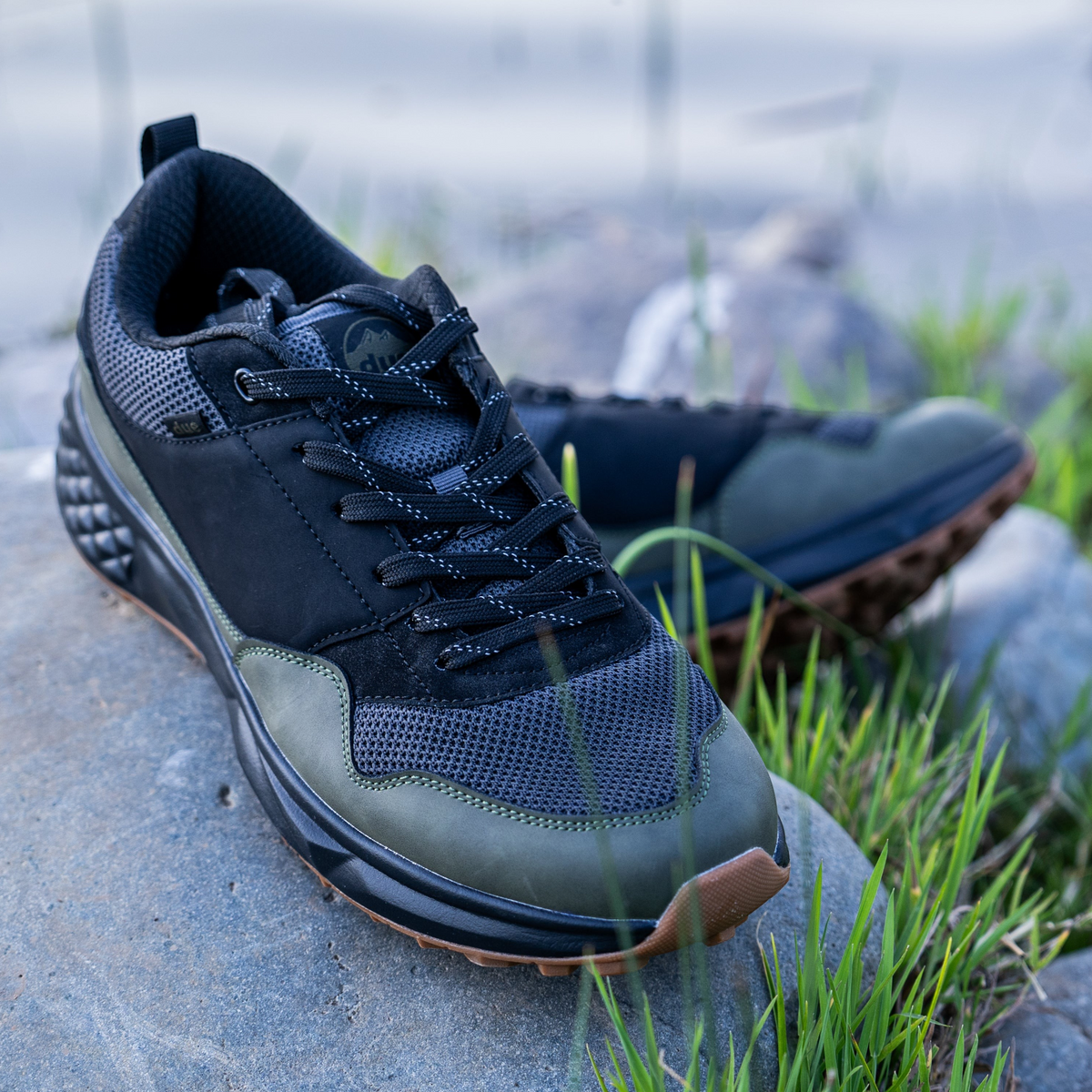Zapatillas Due Shoes Dolomiti verde oliva y negro con suela flexible y diseño transpirable sobre una roca